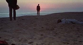 Movie still from “Hickey & Boggs” (1972), directed by Robert Culp – A man standing on the beach at sunset; Extreme Wide shot, Low angle