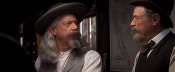 Movie still from “Hidalgo” (2004), directed by Joe Johnston – A man with long grey hair and a beard wearing a cowboy hat; Close Up shot, Over the shoulder angle
