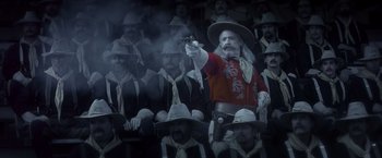 Movie still from “Hidalgo” (2004), directed by Joe Johnston – A man with a gun in front of a group of men; Medium shot, Low angle