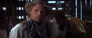 Movie still from “Hidalgo” (2004), directed by Joe Johnston – A man wearing a cowboy hat standing next to a horse; Close Up shot, Low angle
