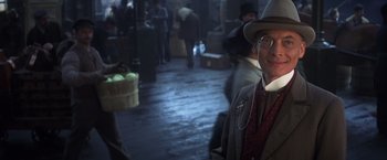Movie still from “Hidalgo” (2004), directed by Joe Johnston – A man in a hat and glasses standing in a market; Close Up shot, Over the shoulder angle