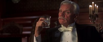 Movie still from “Hidalgo” (2004), directed by Joe Johnston – An older man in a tuxedo holding a glass of water; Close Up shot, Low angle