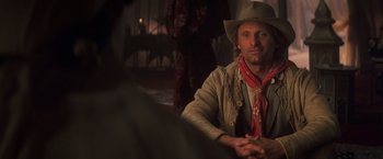 Movie still from “Hidalgo” (2004), directed by Joe Johnston – A man wearing a cowboy hat sitting at a table; Close Up shot, Over the shoulder angle