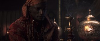 Movie still from “Hidalgo” (2004), directed by Joe Johnston – A man in a red and gold jacket is smoking a hookah; Close Up shot, High angle