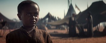 Movie still from “Hidalgo” (2004), directed by Joe Johnston – A young boy standing in front of tents in a field; Close Up shot, Low angle