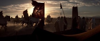 Movie still from “Hidalgo” (2004), directed by Joe Johnston – A group of people standing on top of a sandy beach; Wide shot, Low angle