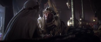 Movie still from “Hidalgo” (2004), directed by Joe Johnston – A man wearing a crown sitting in a room; Close Up shot, Over the shoulder angle
