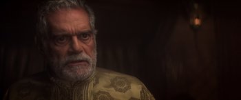 Movie still from “Hidalgo” (2004), directed by Joe Johnston – An older man with a gray beard wearing a yellow and black jacket; Close Up shot, Over the shoulder angle