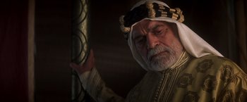 An old man wearing a white hat and a white robe