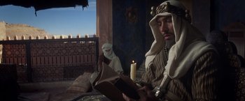 Movie still from “Hidalgo” (2004), directed by Joe Johnston – A man reading a book while a woman sits next to him in front of a candle; Medium shot, Low angle