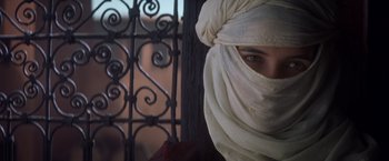 Movie still from “Hidalgo” (2004), directed by Joe Johnston – A woman with a white head covering is standing in front of an iron gate; Close Up shot, Over the shoulder angle