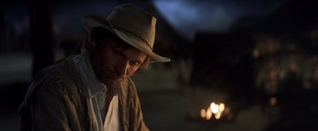 Movie still from “Hidalgo” (2004), directed by Joe Johnston – A man wearing a cowboy hat in the dark; Close Up shot, Over the shoulder angle