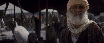 Movie still from “Hidalgo” (2004), directed by Joe Johnston – An old man wearing a turban is in a crowd of people; Close Up shot, Over the shoulder angle