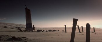 Movie still from “Hidalgo” (2004), directed by Joe Johnston – A person standing on a beach near a pillar; Extreme Wide shot, Low angle