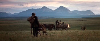 Movie still from “Hidalgo” (2004), directed by Joe Johnston – A group of people riding on the back of a horse drawn carriage; Wide shot, Low angle