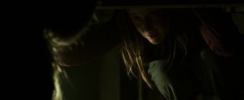 Movie still from “Hidden” (2015), directed by Ross Duffer – A woman with long brown hair is looking at the camera; Medium shot, Low angle