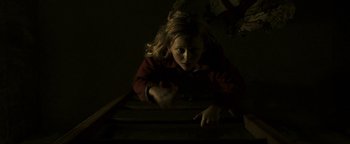Movie still from “Hidden” (2015), directed by Ross Duffer – A young girl is laying on the floor in a dark room; Medium shot, Overhead angle