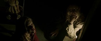 Movie still from “Hidden” (2015), directed by Ross Duffer – Two women sitting on the ground in a dark room; Medium shot, High angle
