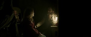 Movie still from “Hidden” (2015), directed by Ross Duffer – A man and a woman sitting next to each other in a dark room; Medium shot, Over the shoulder angle