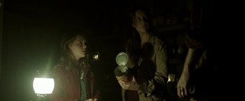 Movie still from “Hidden” (2015), directed by Ross Duffer – Two people standing next to each other in a dark room; Medium shot, Low angle