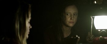 Movie still from “Hidden” (2015), directed by Ross Duffer – A young woman is staring into the camera; Close Up shot, Over the shoulder angle