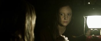 Movie still from “Hidden” (2015), directed by Ross Duffer – A woman looking at her reflection in a mirror; Close Up shot, Over the shoulder angle