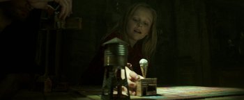 Movie still from “Hidden” (2015), directed by Ross Duffer – A little girl is playing with some toys; Medium shot, High angle