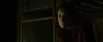 Movie still from “Hidden” (2015), directed by Ross Duffer – A woman is looking at the camera in the dark; Close Up shot, Low angle