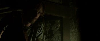 Movie still from “Hidden” (2015), directed by Ross Duffer – A man with long hair is standing in a dark room; Close Up shot, Over the shoulder angle