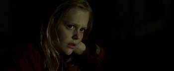 Movie still from “Hidden” (2015), directed by Ross Duffer – A young girl with long blonde hair is looking at the camera; Close Up shot, Low angle