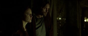 Movie still from “Hidden” (2015), directed by Ross Duffer – A man and a woman standing next to each other in the dark; Medium shot, Low angle