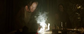 Movie still from “Hidden” (2015), directed by Ross Duffer – A man in a dark room with smoke coming out of his mouth; Medium shot, Low angle