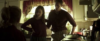 Movie still from “Hidden” (2015), directed by Ross Duffer – A man and a woman standing in a kitchen next to each other; Medium shot, Low angle