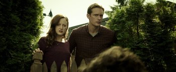 Movie still from “Hidden” (2015), directed by Ross Duffer – A man and a woman standing next to each other near a fence; Medium shot, Low angle