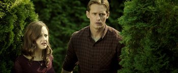 Movie still from “Hidden” (2015), directed by Ross Duffer – A man in a plaid shirt standing next to a tree; Medium shot, Over the shoulder angle