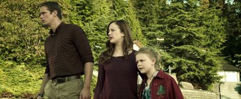 Movie still from “Hidden” (2015), directed by Ross Duffer – Two young people standing next to each other near a tree; Medium shot, Over the shoulder angle