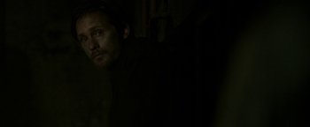 Movie still from “Hidden” (2015), directed by Ross Duffer – A man is looking at the camera in the dark; Close Up shot, Over the shoulder angle