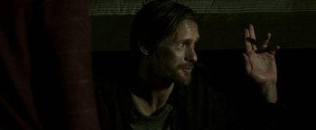 Movie still from “Hidden” (2015), directed by Ross Duffer – A person with long hair and a beard; Close Up shot, Over the shoulder angle