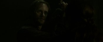 Movie still from “Hidden” (2015), directed by Ross Duffer – A man with long dark hair is looking at the camera; Close Up shot, Over the shoulder angle