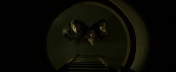 Movie still from “Hidden” (2015), directed by Ross Duffer – Three children sitting on the steps looking up at the camera; Wide shot, Overhead angle