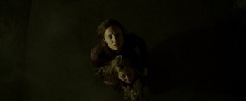 Movie still from “Hidden” (2015), directed by Ross Duffer – A woman and a girl are in a dark room; Medium shot, Overhead angle