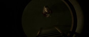 Movie still from “Hidden” (2015), directed by Ross Duffer – A young girl looking up at the top of a flight of stairs; Wide shot, Overhead angle