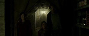 Movie still from “Hidden” (2015), directed by Ross Duffer – A man and a little girl standing in a dark room; Medium shot, Low angle