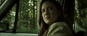 Movie still from “Hidden” (2015), directed by Ross Duffer – A person sitting in a car with trees in the background; Close Up shot, Low angle
