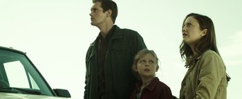 Movie still from “Hidden” (2015), directed by Ross Duffer – A man standing next to a little girl; Medium shot, Low angle