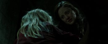 Movie still from “Hidden” (2015), directed by Ross Duffer – A woman looking at another woman in a dark room; Close Up shot, Over the shoulder angle
