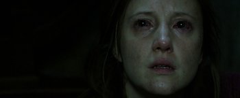Movie still from “Hidden” (2015), directed by Ross Duffer – A person's face with a dark background; Close Up shot, Low angle
