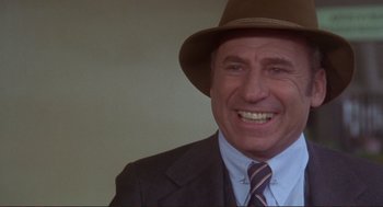 Movie still from “High Anxiety” (1977), directed by Mel Brooks – A man wearing a suit and a hat smiling for the camera; Close Up shot, High angle