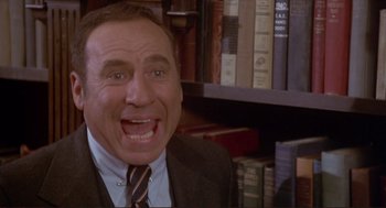 Movie still from “High Anxiety” (1977), directed by Mel Brooks – A man in a suit and tie in front of a book shelf; Close Up shot, High angle