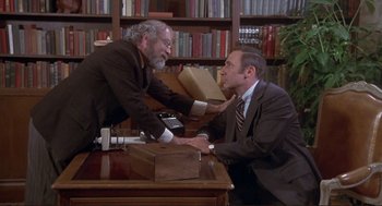 Movie still from “High Anxiety” (1977), directed by Mel Brooks – Two men in business suits sitting at a desk; Medium shot, High angle